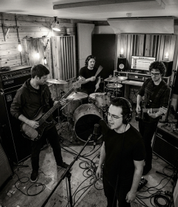Black and white photograph of Nevan Lochlann, Eoin Belfield, Jesse Rómlárson and Jon Gilmour performing together during an early Eventstellar recording session at Nevan's studio in Bray, County Wicklow, Ireland in 2017