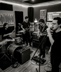 Black and white photograph of Eventstellar members Nevan Lochlann, Eoin Belfield, Jon Gilmour and Jesse Rómlárson recording together in a Dublin recording studio during the band's early recording sessions in 2017