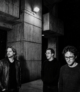 Black and white photograph of Nevan Lochlann, Jesse Rómlárson and J.J. Gilmour outside University College Dublin after an early Eventstellar performance in 2017