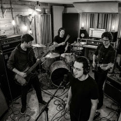Black and white photograph of Nevan Lochlann, Eoin Belfield, Jesse Rómlárson and Jon Gilmour performing together during an early Eventstellar recording session at Nevan's studio in Bray, County Wicklow, Ireland in 2017