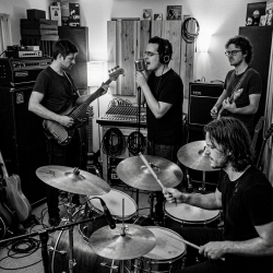 Black and white photograph of Eventstellar members Nevan Lochlann, Eoin Belfield, Jesse Rómlárson and Jon Gilmour performing together during an early recording session at Nevan's studio in Bray, County Wicklow, Ireland in 2017