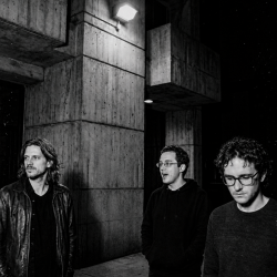 Black and white photograph of Nevan Lochlann, Jesse Rómlárson and J.J. Gilmour outside University College Dublin after an early Eventstellar performance in 2017