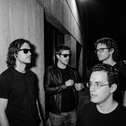 Black and white photograph of Nevan Lochlann, Jesse Rómlárson, J.J. Gilmour and Eoin Belfield outside University College Dublin during an early Eventstellar gathering in 2017