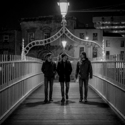The three members of Sojourner walking across the Ha'penny Bridge in Dublin at night after a day exploring the city