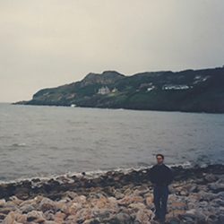 A lone traveler standing on the rocky shoreline in Howth during an early visit to Ireland captured on color film