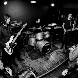 Eventstellar performing in a small Bray venue while audience members gather around the stage with drinks in hand