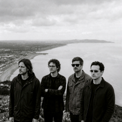 Black and white photograph of Nevan Lochlann, Jesse Rómlárson, Eoin Belfield and J.J. Gilmour overlooking the Irish Sea from Bray Head in County Wicklow, Ireland in 2017