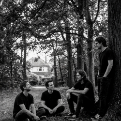 Black and white photograph of Jesse Rómlárson, Eoin Belfield, Nevan Lochlann and J.J. Gilmour relaxing together at Deer Park in Mount Merrion, Dublin, Ireland in 2017
